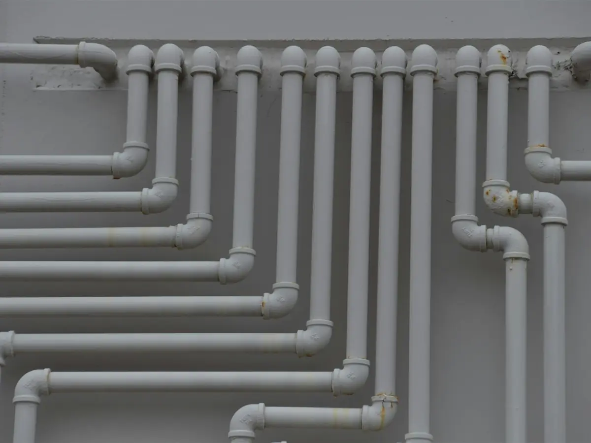 Rows of new gray plastic supply pipes mounted on a wall