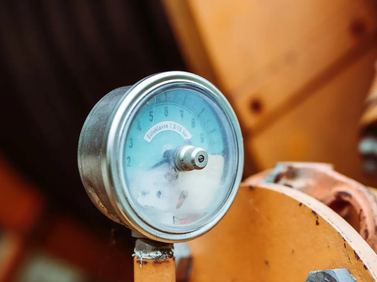 A round pressure gauge mounted on an orange tank