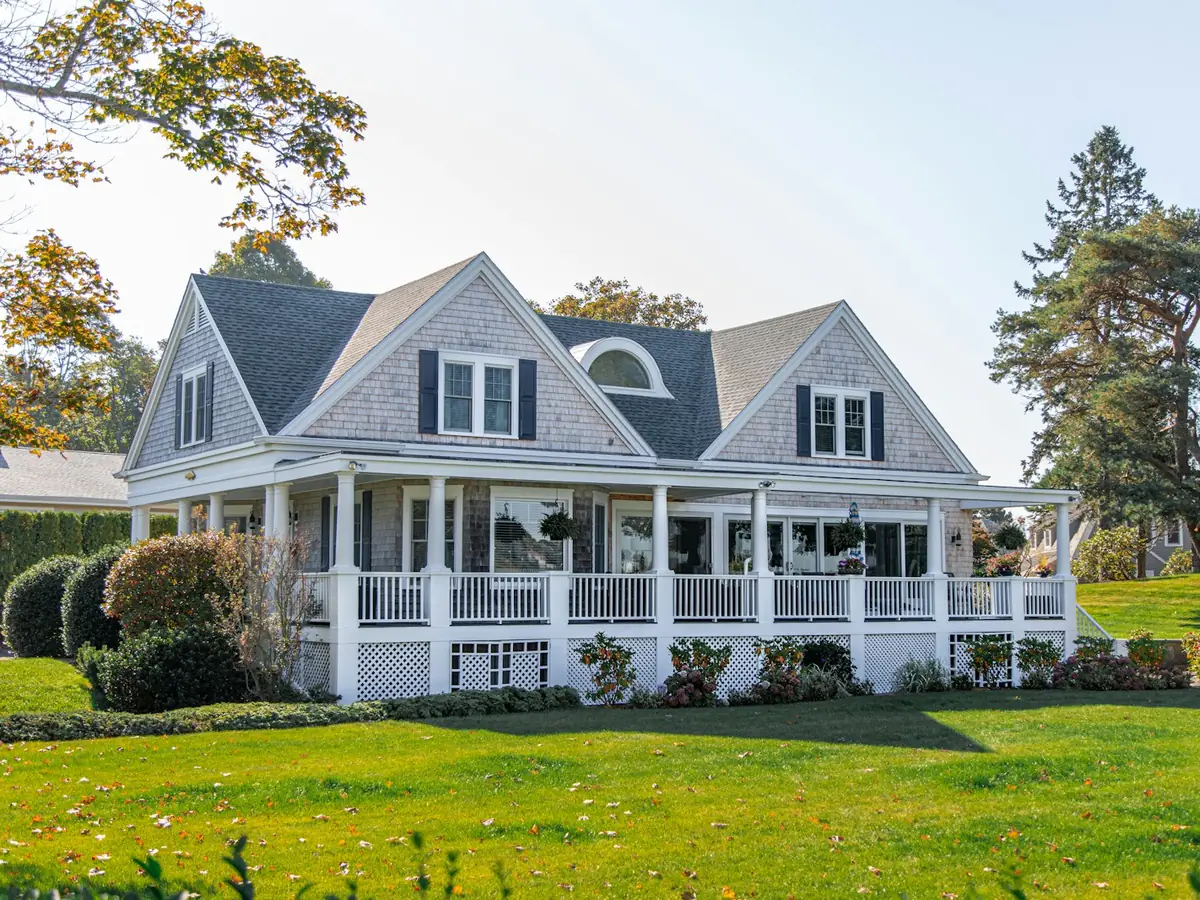 A large two-story house with a wraparound porch and a green lawn